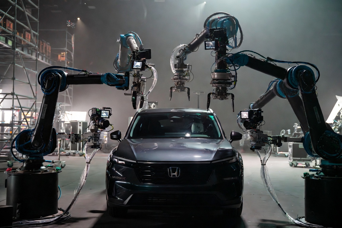 Blue robotic arms surrounding dark Honda vehicle
